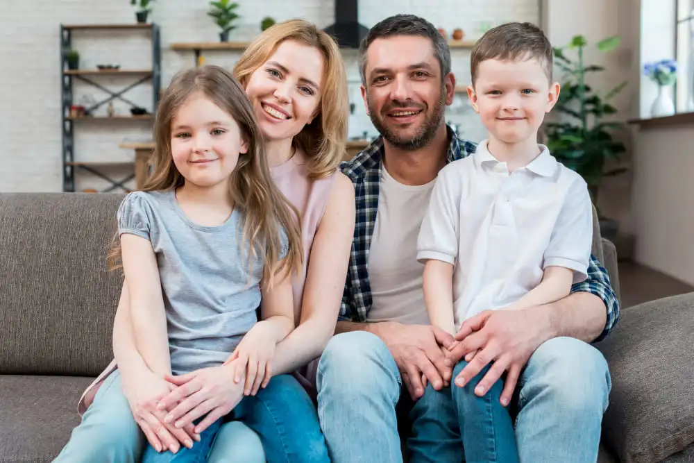 O familie cu doi copii fericiți și sănătoși pe o canapea.